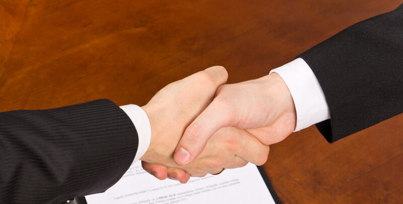 Businessmen hand shake after signing the agreement.